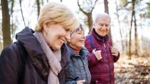 Gruppo di tre anziani passeggiano in un parco in autunno